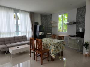 Una sala de estar con un sofá, una mesa y sillas. en Wildflower phangan, en Haad Pleayleam