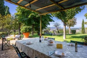 a table with wine bottles and glasses on a patio at Maria Gabriella Holiday Home In Monticchiello in Monticchiello