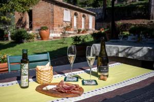 a table with two bottles and two glasses of wine at Maria Gabriella Holiday Home In Monticchiello in Monticchiello