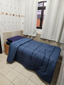 a blue bed in a room with a window at Quarto suite 50mts Metro Guilhermina-Esperança in Sao Paulo