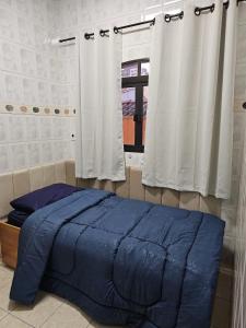 a bedroom with a blue bed and a window at Quarto suite 50mts Metro Guilhermina-Esperança in Sao Paulo +2 photos