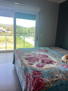 ボンビーニャスにあるSua casa fora de casaのベッドルーム1室(花の毛布付きのベッド1台付)