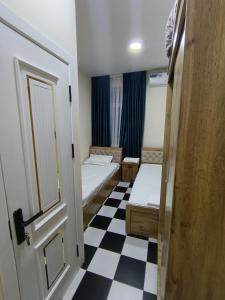 Una pequeña habitación con dos camas y suelo de cuadros. en Hotel, en Sergeli