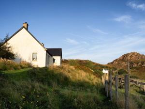 Una vieja casa blanca en una colina con una valla. en 1 Bed in Kinlochbervie 86897, en Rhiconich