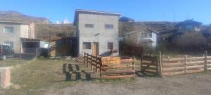 een huis met een hek naast een gebouw bij Berberis Apart in El Chalten