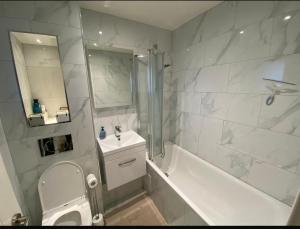 a white bathroom with a sink and a tub and a shower at Modern private room in London