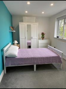 a bedroom with a bed with a purple blanket at Modern private room in London