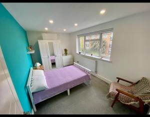 a bedroom with a purple bed and a window at Modern private room in London