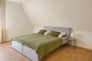 a bedroom with a bed with green sheets and a table at Hotel Weisses Lamm in Bruchsal