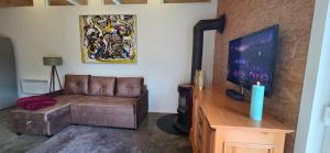 a living room with a couch and a flat screen tv at Ferienhaus LODA - Garten, Netflix & Spreewald Flair in Heinersbrück