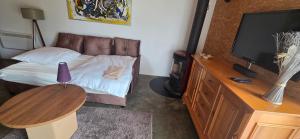 a bedroom with a bed with a television and a table at Ferienhaus LODA - Garten, Netflix & Spreewald Flair in Heinersbrück +13 photos