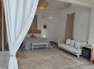 a bedroom with a bed and a couch at Villa A'Kabar Guest House in Aït Benhaddou