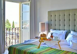 a bed with a table with a tray of food on it at Noble House Essence Évora - by Unlock Hotels in Évora