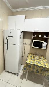 a kitchen with a white refrigerator and a microwave at Mongaguá Apartamento in Mongaguá