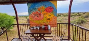 a table on a balcony with a painting of flowers at Blomwaens Adam se Uitspanning in Orania