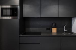 a black kitchen with a sink and a microwave at Ciasa Anteriol in San Cassiano +4 photos