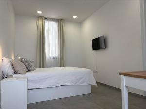 a white bedroom with a bed and a television at playa honda airport suite in Playa Honda