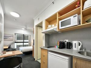 Una pequeña cocina con fregadero y microondas. en Brisbane Apt Near Dining Shops and River Walks, en Brisbane