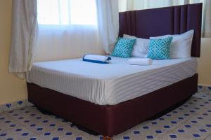 Una cama grande con dos almohadas encima. en Little escalade, en Mombasa