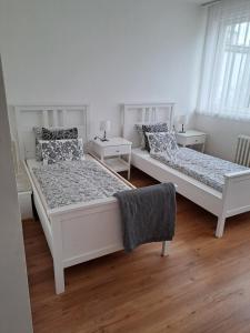 two beds in a white room with two tables at Apartmans MWM Brno 3 in Brno