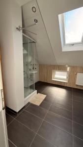 une chambre mansardée avec une douche en verre et une fenêtre dans l'établissement Übernachtung by Tag, à Cassel