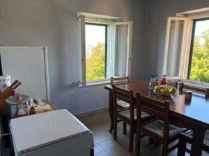 a kitchen with a table and chairs and windows at La Loggia dei Fabbri - Montefabbri in Monte Fabbri