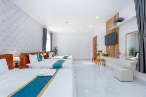 a hotel room with two beds and a television at Villas & Hotel 126 Vũng Tàu in Vung Tau