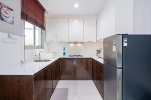 a kitchen with a stainless steel refrigerator and wooden cabinets at Sorrento Pool Villa Naga Jomtien Pattaya in Na Jomtien