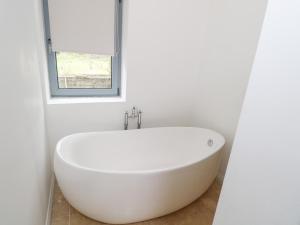 Una bañera blanca en un baño con ventana. en Sruthan Lodge, en Cornamucklagh South 40 fotos más