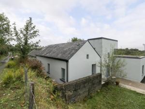una casa blanca con techo negro en Sruthan Lodge, en Cornamucklagh South