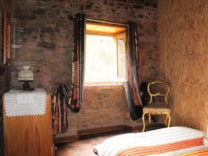 a bedroom with a bed and a window and a chair at Casa do Moinho Novo in Fontão Fundeiro