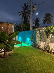 a backyard at night with a blue wall at Chalés XIÉ in São Miguel dos Milagres +56 photos