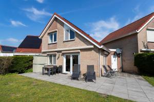 a patio with chairs and a table in front of a house at Mosselbank 073 - Noordzeepark Ouddorp in Ouddorp