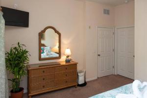una camera da letto con un comò con uno specchio di Disney Area Vacation Kissimmee a Kissimmee Altre 72 foto