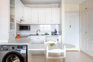 a white kitchen with a sink and a dishwasher at Tranquilidad frente al mar by CABANA Rentals in Arona