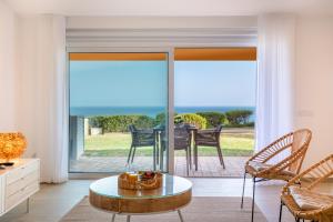 un soggiorno con porte scorrevoli in vetro, tavolo e sedie di The Oceanfront Studio Luz VR110 a Luz