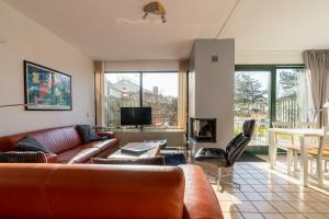 a living room with a leather couch and a tv at Veermansplaat 25 - Noordzeepark Ouddorp NOT FOR COMPANIES!! in Ouddorp