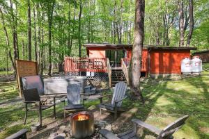 a cabin in the woods with chairs and a fire pit at Pet Friendly Lake Retreat With Hot Tub & Fire Pit in Locust Lakes Village