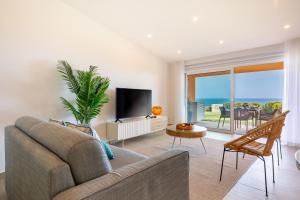 un soggiorno con un divano e una TV di The Oceanfront Studio Luz VR110 a Luz