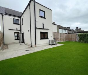 ein weißes Haus mit einem Garten mit grünem Gras in der Unterkunft Sunberry 2 Bright Modern Entire Home, Headford in Headford
