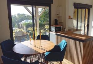 a kitchen with a wooden table and chairs and a counter at L'Escapade in Villers-sur-le-Roule