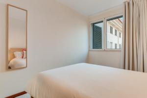 una camera da letto con un letto bianco e uno specchio di Funchal City Nest a Funchal Altre 15 foto