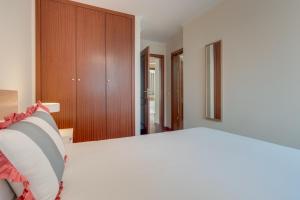 una camera da letto con un letto bianco e un armadio in legno di Funchal City Nest a Funchal