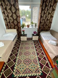 a room with two beds and a rug on the floor at Kf guest house 2 in Shabdan