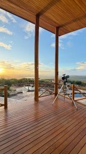 a camera on a wooden deck with the sun setting at Chalé Vivenda dos Ventos in Serra de São Bento