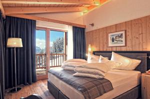 a bedroom with a bed with pillows and a balcony at Alpine Hotel Gran Foda' in San Vigilio Di Marebbe