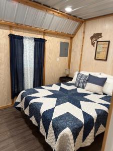 a bedroom with a black and white comforter on a bed at Trails , Tails , and Scales Cabin 2 in Burkeville