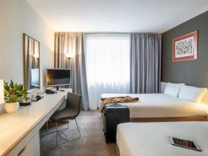 a hotel room with two beds and a desk at Novotel Glasgow Centre in Glasgow