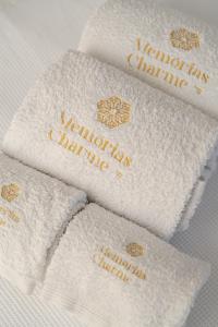 a group of white towels with gold writing on them at Memórias Charme Residences in Covilhã +65 photos