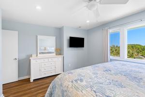 a bedroom with a bed and a tv and a window at Mariner's Walk 5F - Ocean View Condo! Pool! in Isle of Palms